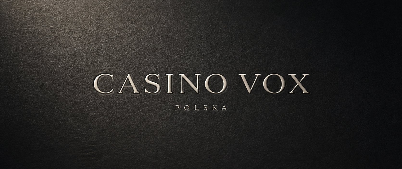 Wordmark Casino Vox wytłoczony na matowej, grafitowej powierzchni